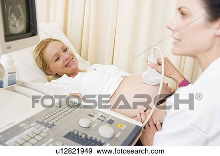 Pregnant woman getting ultrasound from doctor View Large Photo Image Stock Photo - Pregnant woman getting ultrasound from doctor. Fotosearch