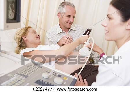 Pregnant woman getting ultrasound from doctor with husband looking at picture View Large Photo Image Stock Photo - Pregnant woman getting ultrasound from doctor with husband looking at picture. Fotosearch