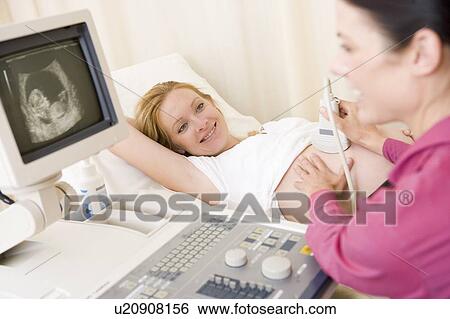 Stock Photograph - Pregnant woman getting ultrasound from doctor. Fotosearch