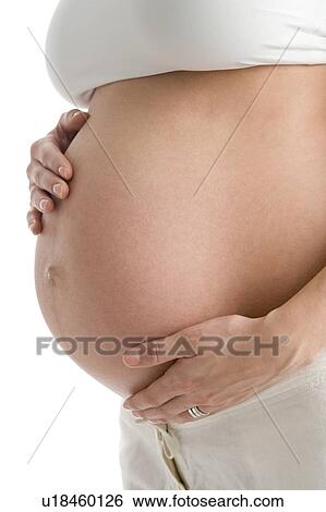 Stock Photograph - Pregnant woman holding exposed belly. Fotosearch
