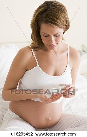 Stock Image - Pregnant woman in bedroom with medicine. Fotosearch