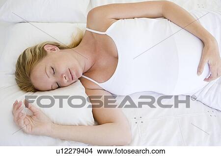 Pregnant woman lying in bed sleeping View Large Photo Image Picture - Pregnant woman lying in bed sleeping. Fotosearch