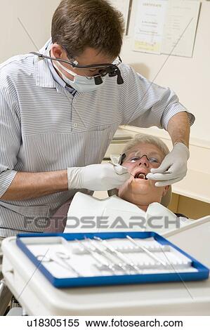 Stock Photography - Dentist in exam room with woman in chair. Fotosearch