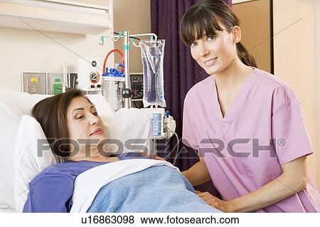 Stock Photo - Nurse Helping Senior Woman Lying In Hospital Bed. Fotosearch