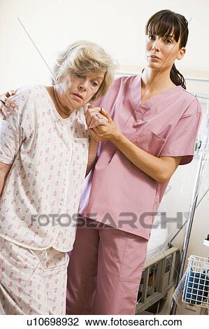 Stock Image - Nurse Helping Senior Woman To Walk. Fotosearch