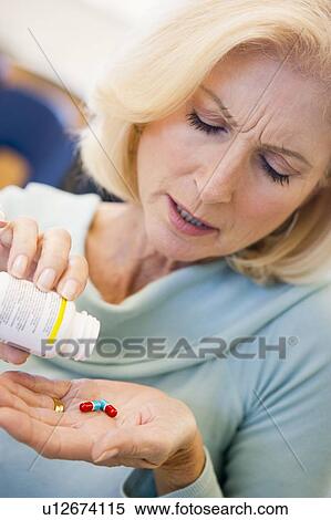 Stock Photography - Senior Woman Pouring Pills Out Of Bottle. Fotosearch