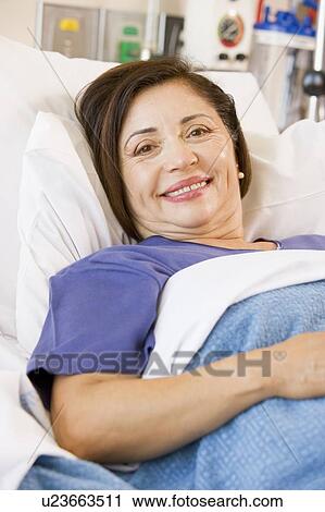 Stock Image - Senior Woman Smiling, Lying In Hospital Bed. Fotosearch
