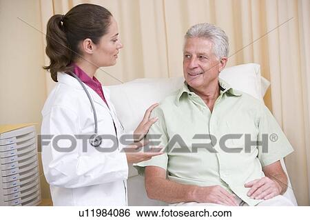Doctor giving checkup to man in exam room smiling View Large Photo Image Stock Photograph - Doctor giving checkup to man in exam room smiling. Fotosearch