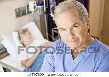 Stock Image - Doctor Standing In Patients Room, Looking Serious. Fotosearch