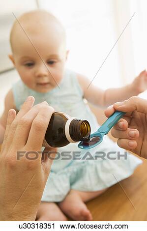 Mother giving baby medicine indoors View Large Photo Image Stock Image - Mother giving baby medicine indoors. Fotosearch
