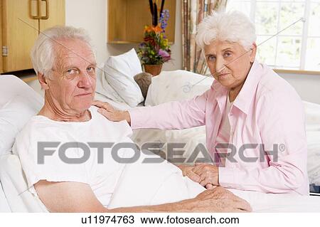 Stock Image - Senior Couple Sitting In Hospital, Looking Serious. Fotosearch