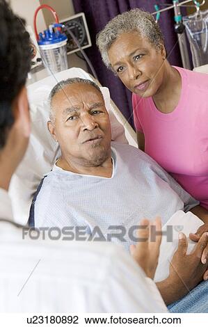 Stock Image - Senior Couple Talking To Doctor. Fotosearch