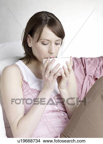 Picture - Woman drinking from a bowl. Fotosearch