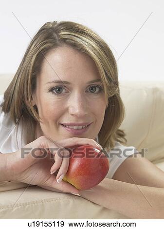 Woman on the sofa with an apple View Large Photo Image Stock Photo - Woman on the sofa with an apple. Fotosearch