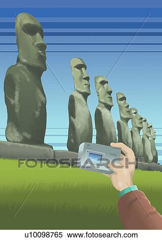 Stock Illustration - Close-up of a person's hand taking a picture of ancient statues, Moai Statues, Ahu Tongariki, Easter Island, Chile. Fotosearch