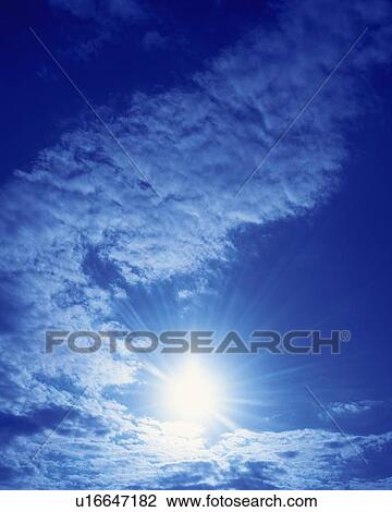 Stock Image - Blue sky and Clouds, Low angle view, Lens Flare. Fotosearch