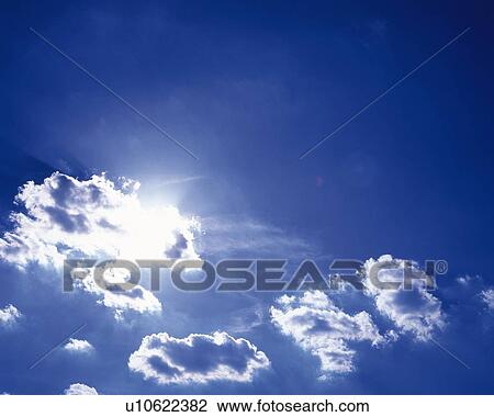 Stock Image - Blue sky and Clouds with Sun, Low angle view. Fotosearch