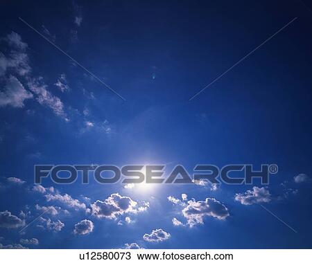 Stock Image - Blue sky and Clouds with Sun, Low angle view. Fotosearch