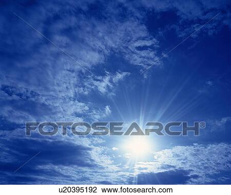 Stock Image - Blue sky and Clouds with Sun, Low angle view, Lens Flare. Fotosearch