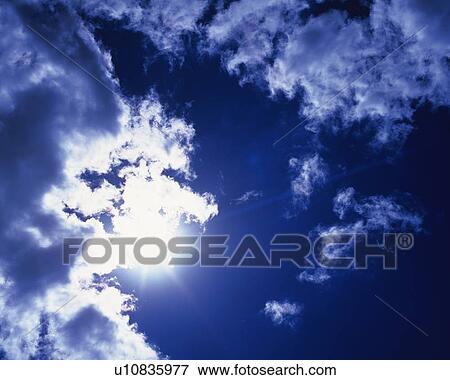 Stock Photo - Blue sky and Clouds with Sun, Low angle view. Fotosearch