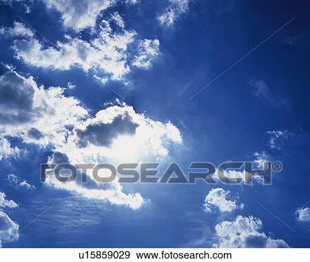 Stock Photo - Blue sky and Clouds with Sun, Low angle view. Fotosearch