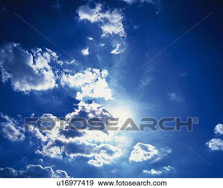 Stock Photo - Blue sky and Clouds with Sun, Low angle view. Fotosearch