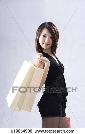 Stock Photo - Young woman holding shopping bags over shoulder. Fotosearch