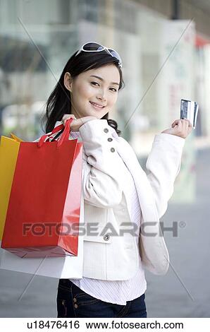 Young woman holding shopping bags over shoulder with bank cards in her hand View Large Photo Image Stock Photograph - Young woman holding shopping bags over shoulder with bank cards in her hand. Fotosearch