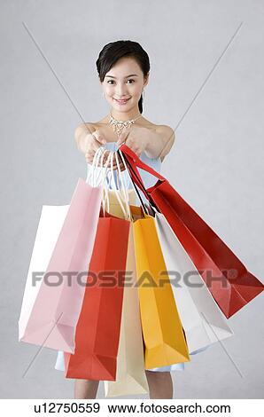 Young woman in formal dress raising shopping bags in front View Large Photo Image Stock Photo - Young woman in formal dress raising shopping bags in front. Fotosearch