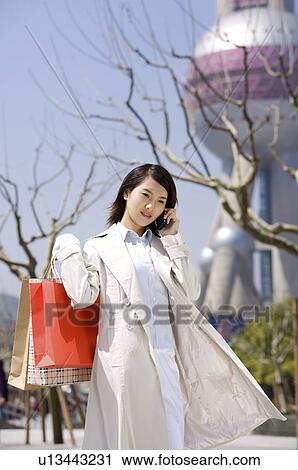 Young woman on the phone holding shopping bags View Large Photo Image Stock Image - Young woman on the phone holding shopping bags. Fotosearch