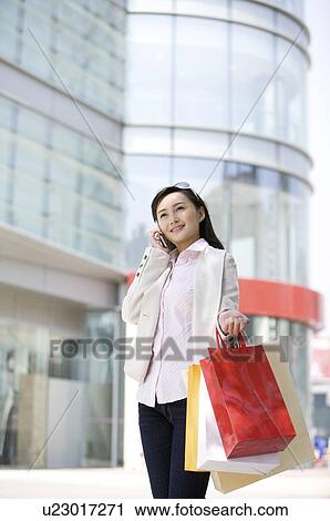 Stock Image - Young woman on the phone with shopping bags. Fotosearch