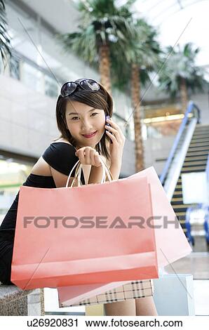Stock Image - Young woman on the phone with shopping bags. Fotosearch