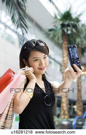 Young woman photographing herself at shopping mall View Large Photo Image Stock Photo - Young woman photographing herself at shopping mall. Fotosearch