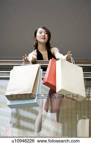 Stock Photograph - Young woman putting shopping bags in front of banisters. Fotosearch