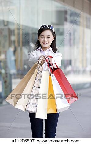 Stock Photo - Young woman raising shopping bags in front. Fotosearch