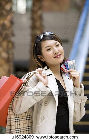 Young woman showing her bank cards with shopping bags over her shoulder View Large Photo Image Stock Photo - Young woman showing her bank cards with shopping bags over her shoulder. Fotosearch