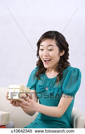 Stock Photography - Young woman surprising at gift box. Fotosearch