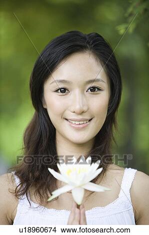 Young woman holding flower outdoors View Large Photo Image Picture - Young woman holding flower outdoors. Fotosearch