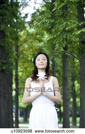 Stock Photo - Young woman holding flower outdoors. Fotosearch