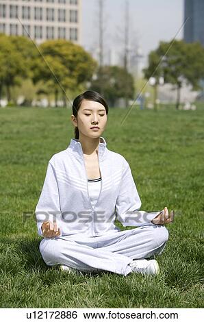 Young woman in lotus position on lawn View Large Photo Image Stock Photograph - Young woman in lotus position on lawn. Fotosearch