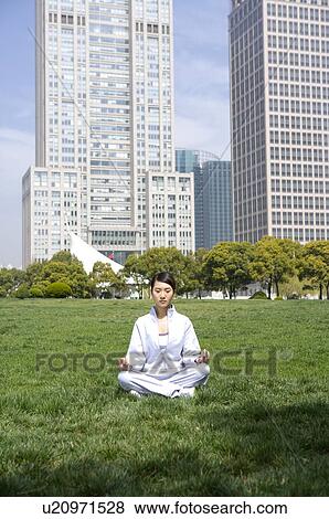 Young woman in lotus position sitting on lawn View Large Photo Image Stock Photo - Young woman in lotus position sitting on lawn. Fotosearch