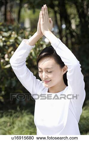 Stock Image - Young woman in prayer position outdoors. Fotosearch