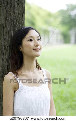 Young woman leaning on tree View Large Photo Image Stock Photo - Young woman leaning on tree. Fotosearch