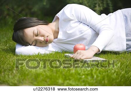 Young woman lying on lawn napping outdoors View Large Photo Image Stock Photo - Young woman lying on lawn napping outdoors. Fotosearch