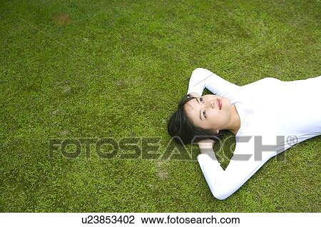 Young woman lying on lawn View Large Photo Image Stock Image - Young woman lying on lawn. Fotosearch
