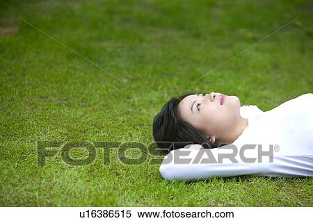 Stock Photography - Young woman lying on lawn. Fotosearch