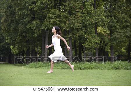 Young woman running on lawn View Large Photo Image Stock Image - Young woman running on lawn. Fotosearch