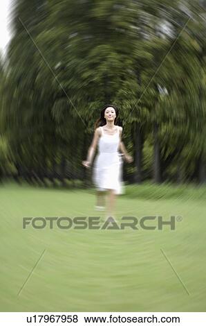 Stock Photo - Young woman running on lawn. Fotosearch