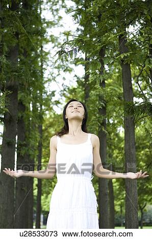 Young woman standing and breathing deep in park View Large Photo Image Stock Image - Young woman standing and breathing deep in park. Fotosearch