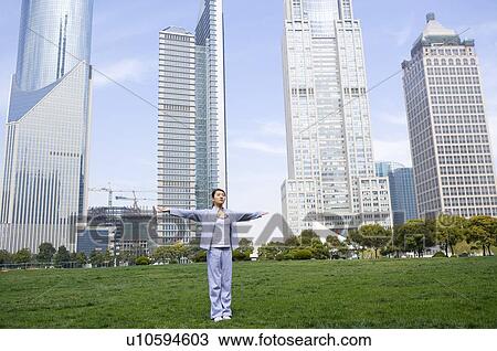 Young woman standing on lawn, buildings in the background View Large Photo Image Stock Image - Young woman standing on lawn, buildings in the background. Fotosearch